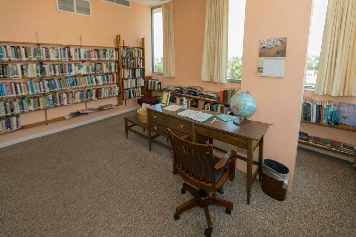 A cozy library corner with a desk, bookshelf, and globe.