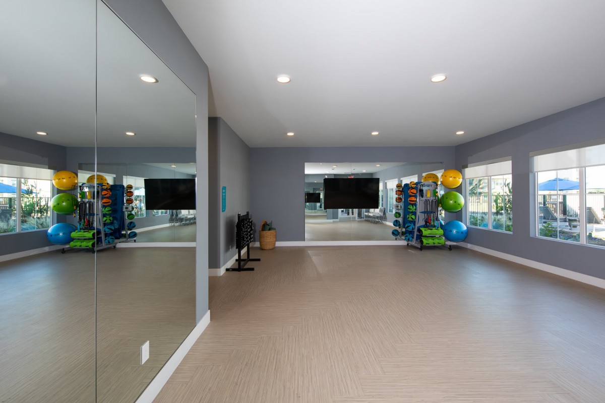 An empty fitness room equipped with mirrors, yoga balls, and various exercise equipment.