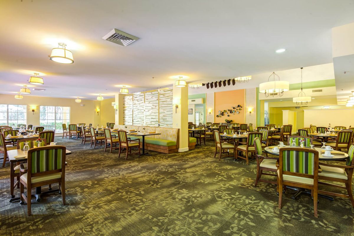 A spacious and well-decorated dining area with multiple tables and chairs, featuring soft lighting.
