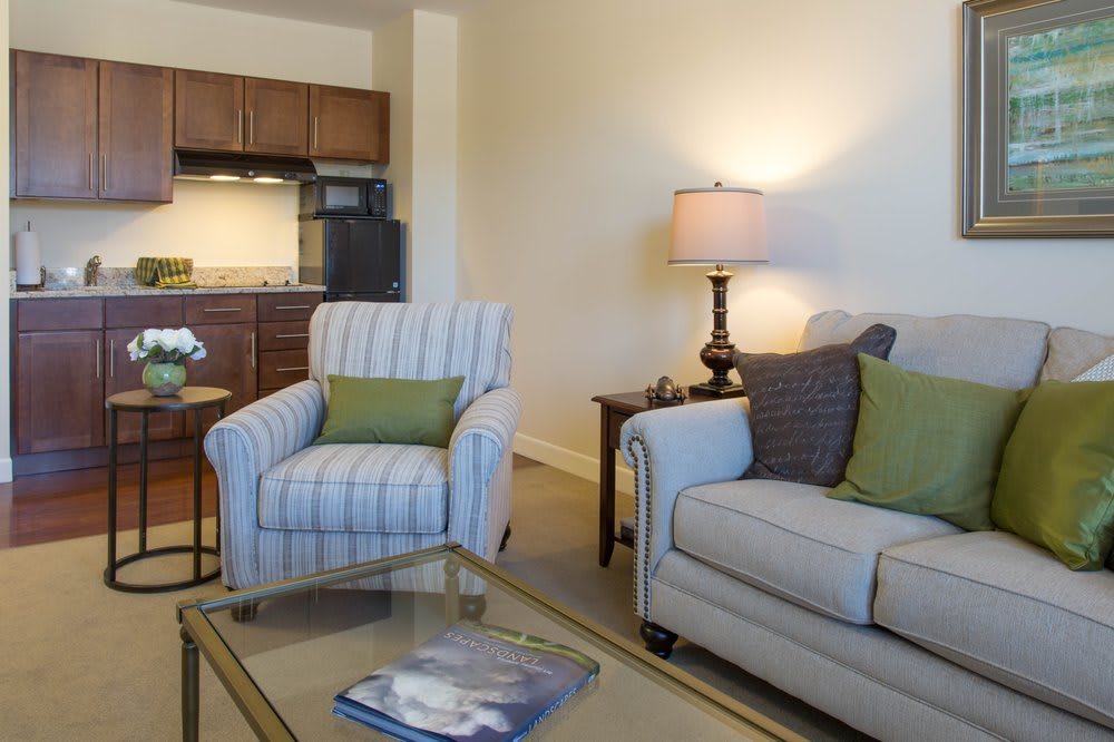 A cozy living room with a sofa, armchair, and a lamp beside a coffee table.