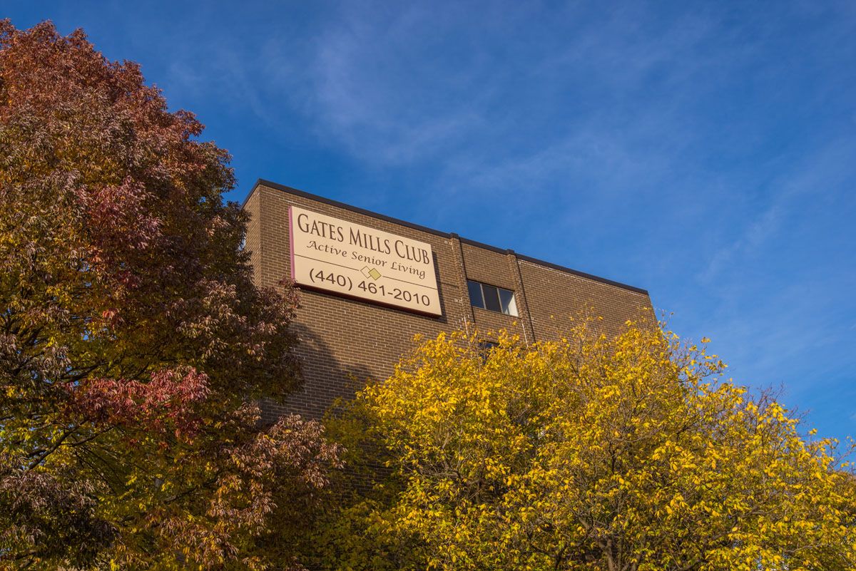 A building with a sign, surrounded by autumn trees under a clear blue sky.