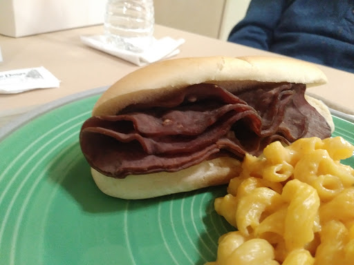 A delicious beef sandwich served with a side of creamy macaroni and cheese.