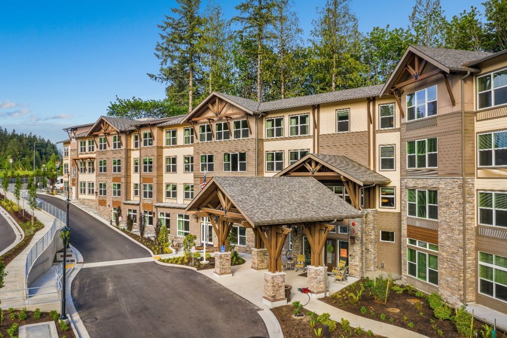 A modern residential building with a wooden exterior surrounded by trees.