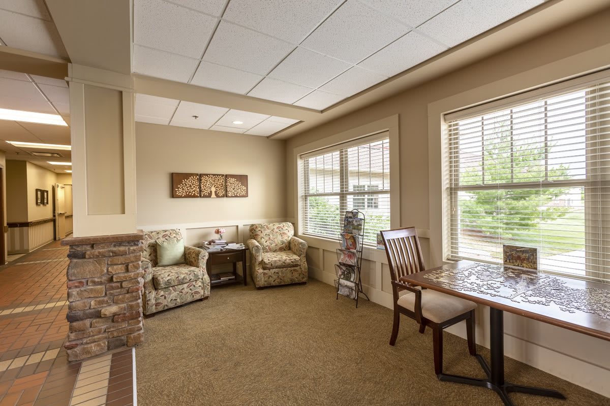 A cozy living room with comfortable chairs, a small wooden table, and large windows letting in natural light.
