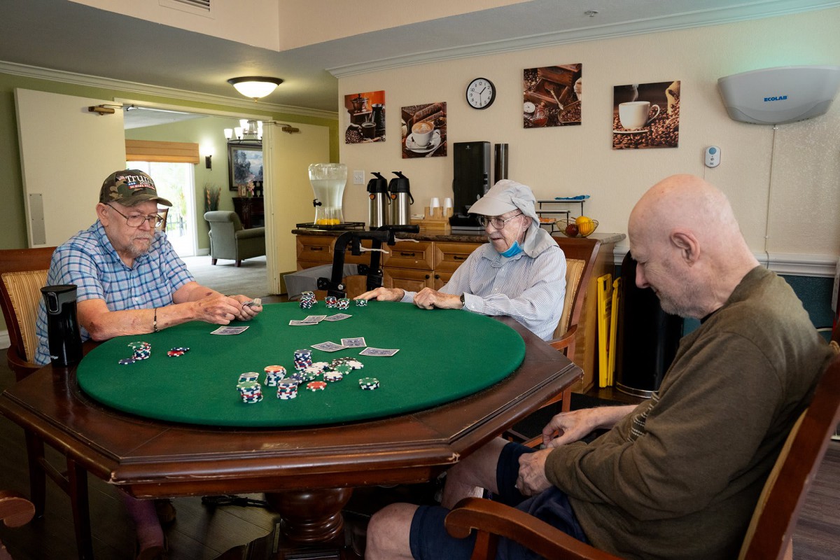 Elderly individuals enjoying a game of poker at a round table indoors.