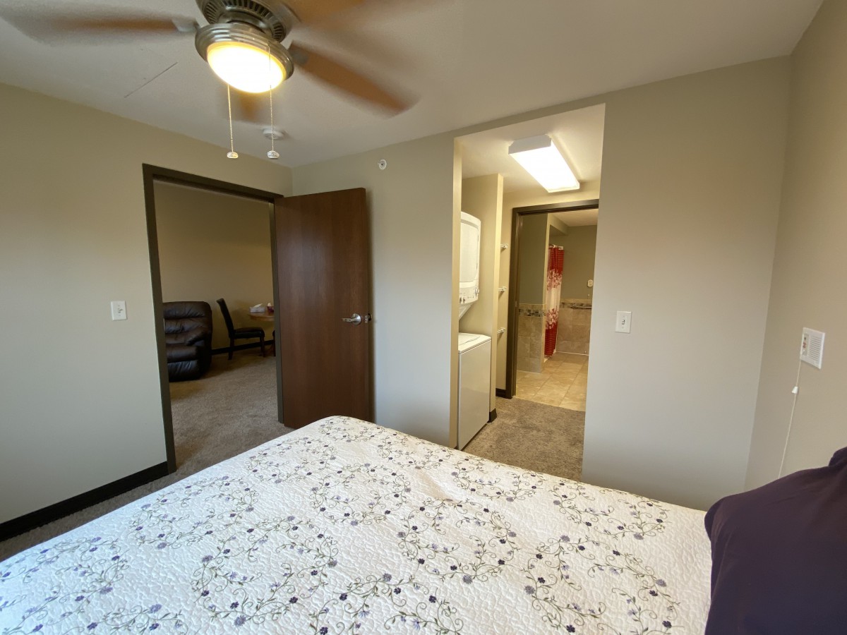 A cozy bedroom with a ceiling fan and visible entrance to an adjoining room.