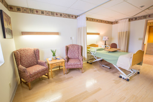 A well-furnished hospital room with comfortable seating and a patient bed.