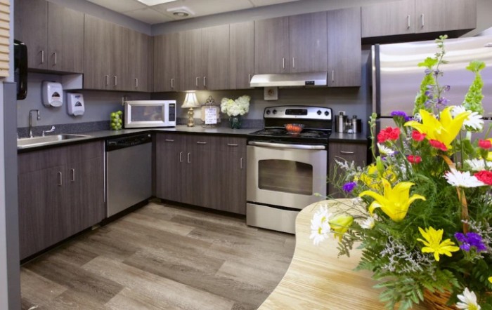 A modern kitchen with stainless steel appliances and a colorful floral arrangement on the counter.