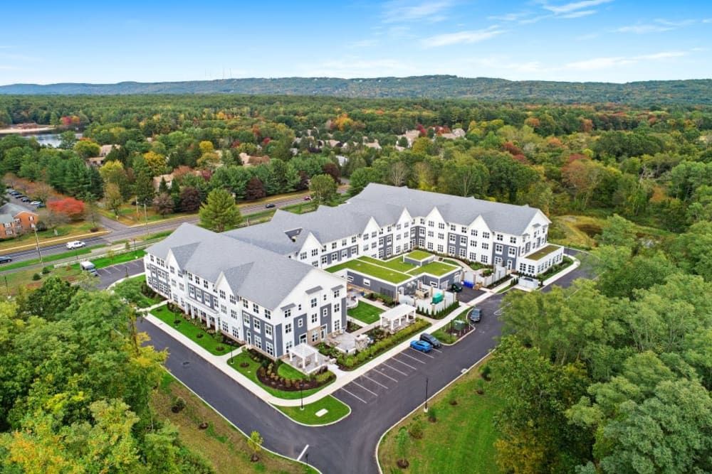 An aerial view of a large residential building surrounded by greenery and parking lots.