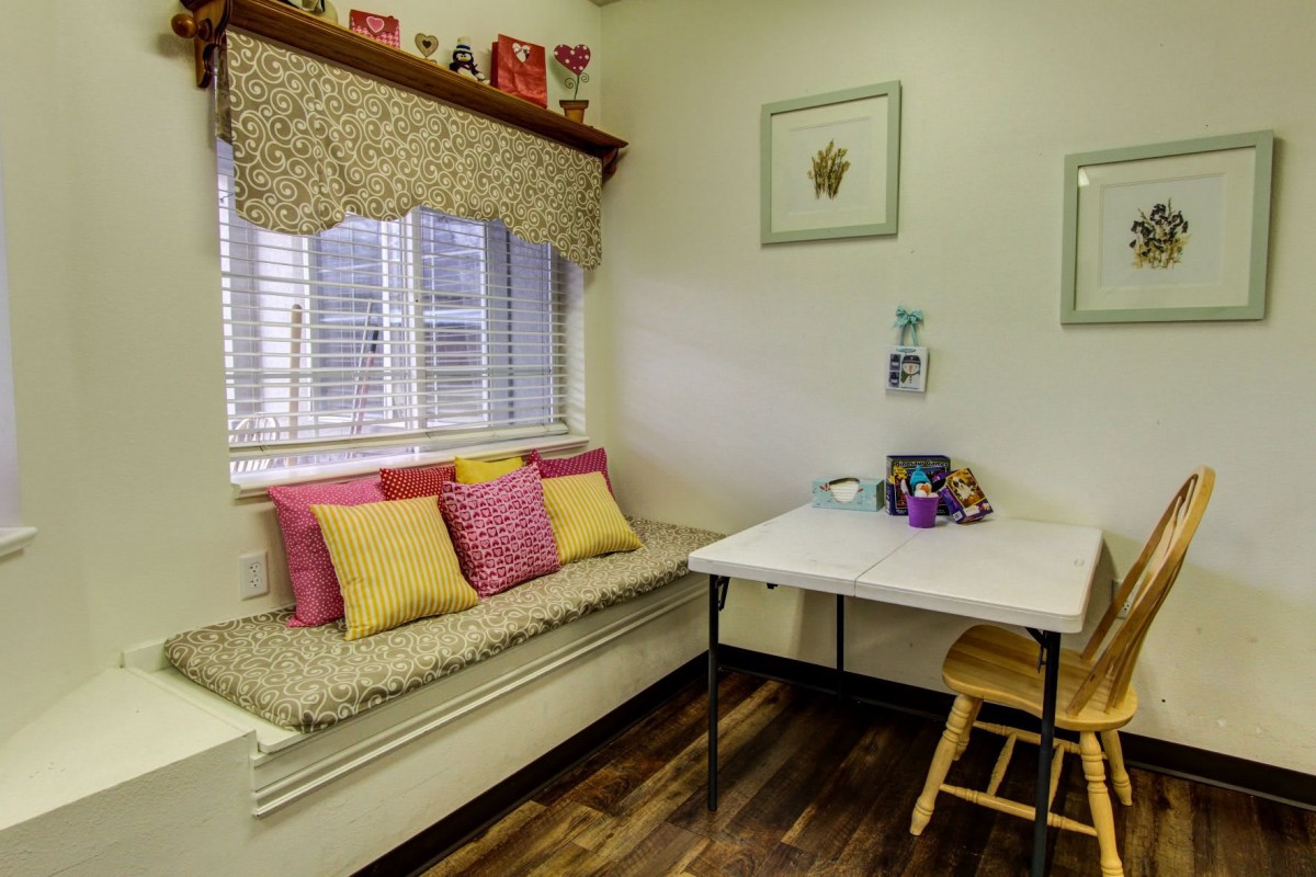 A cozy room with a window seat adorned with colorful pillows and a small table set up for activities.