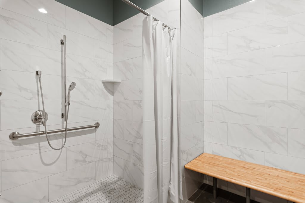 Accessible shower area with a bench and grab bar.