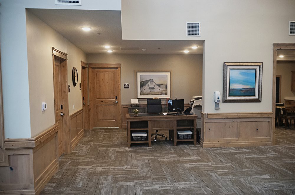 A tidy office reception area with a central desk and wall artwork.