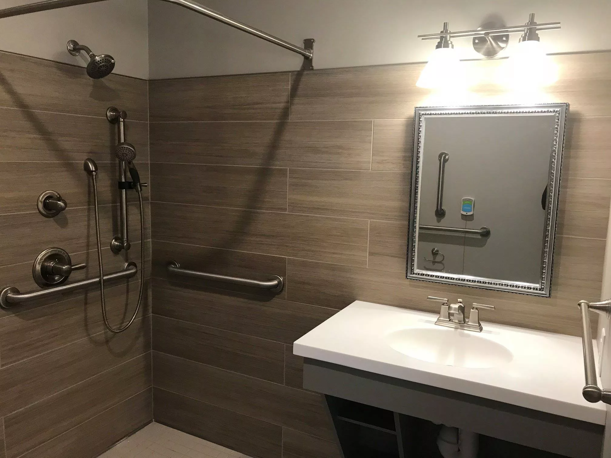 A modern bathroom featuring a shower area, sink with a mirror, and contemporary lighting.