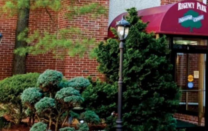 A charming scene with a brick building, lamp post, and lush greenery under a red canopy.