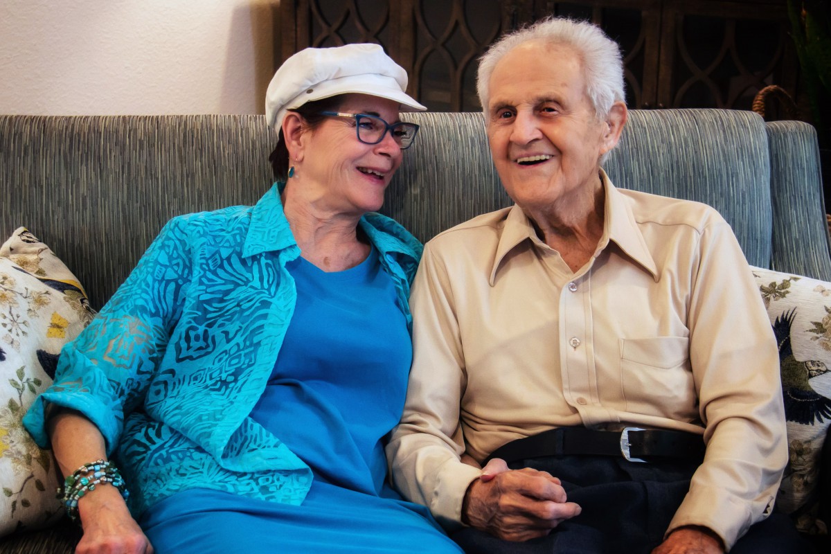 An elderly couple sitting together, sharing a joyful moment.