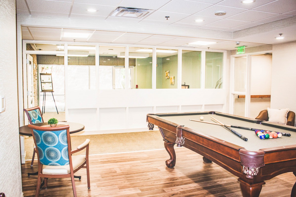 A brightly lit game room with a pool table and seating.