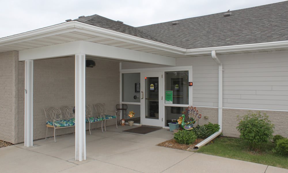An exterior view of a building entrance with an overhang and chairs.