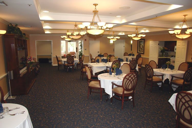 An elegant dining room with neatly arranged tables and chairs, adorned with chandeliers.