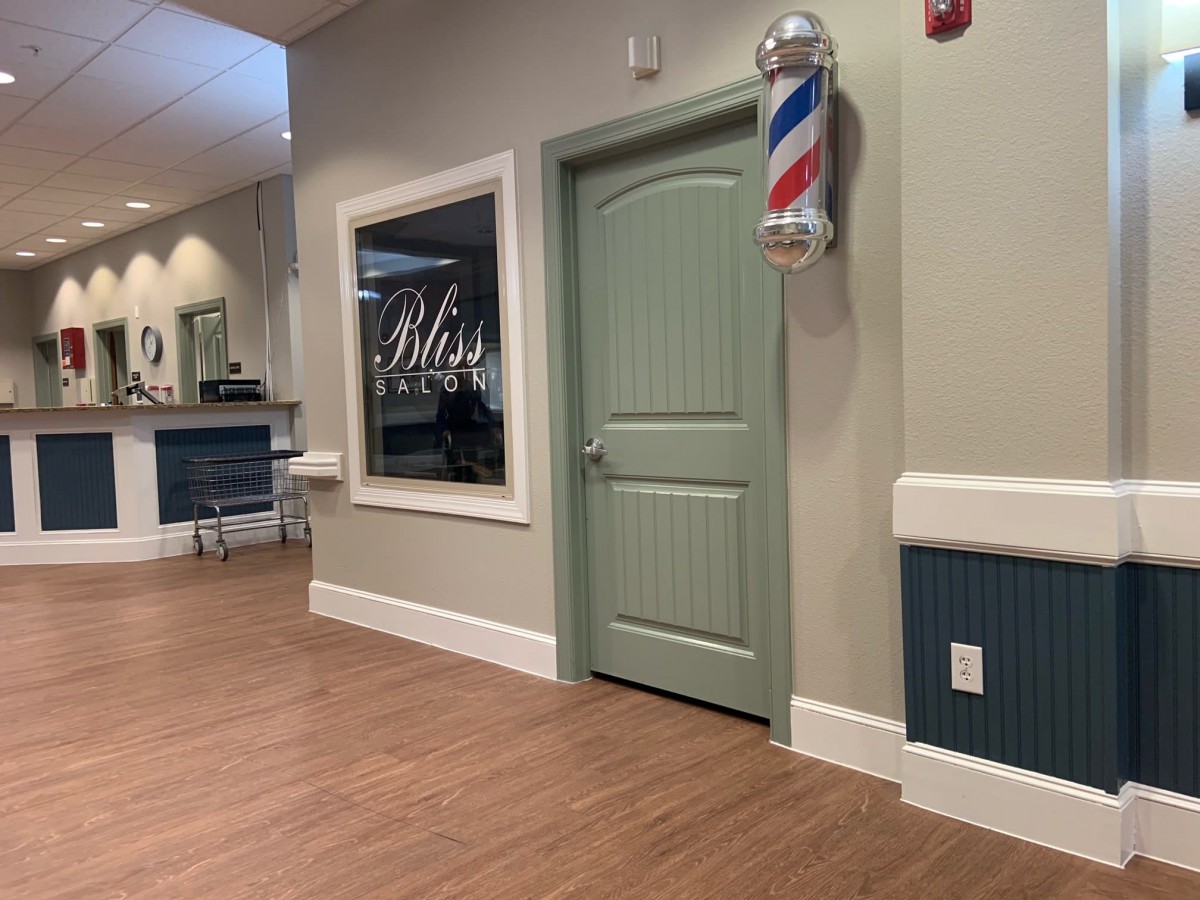 The interior of a barbershop featuring a closed door with a barber pole and a waiting area.
