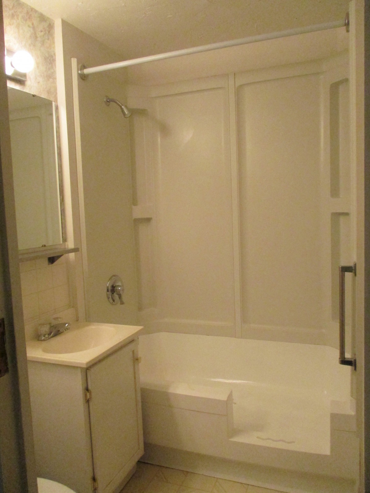 A bathroom with a bathtub and shower, featuring a sink and mirror.