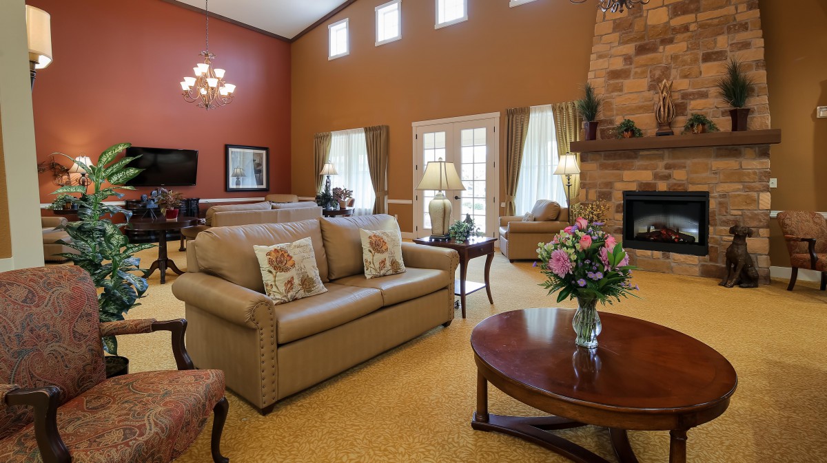 A cozy living room featuring a comfortable sofa, coffee table, and a fireplace, decorated with warm colors and elegant furnishings.