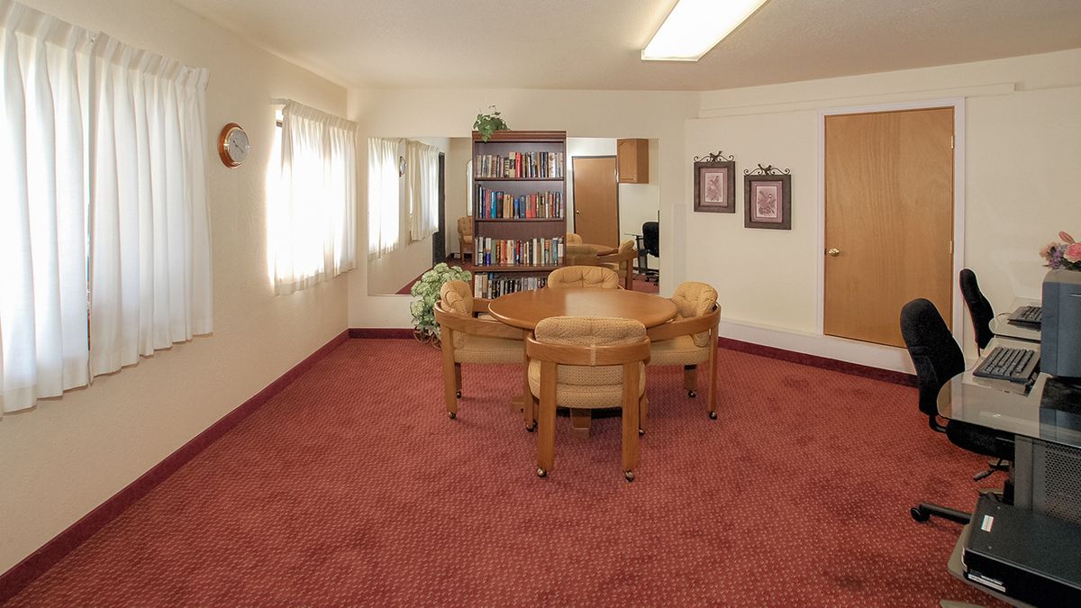 A cozy living room with a table, chairs, and a bookshelf.