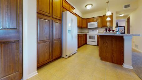 A kitchen with wooden cabinets, modern appliances, and bright lighting.