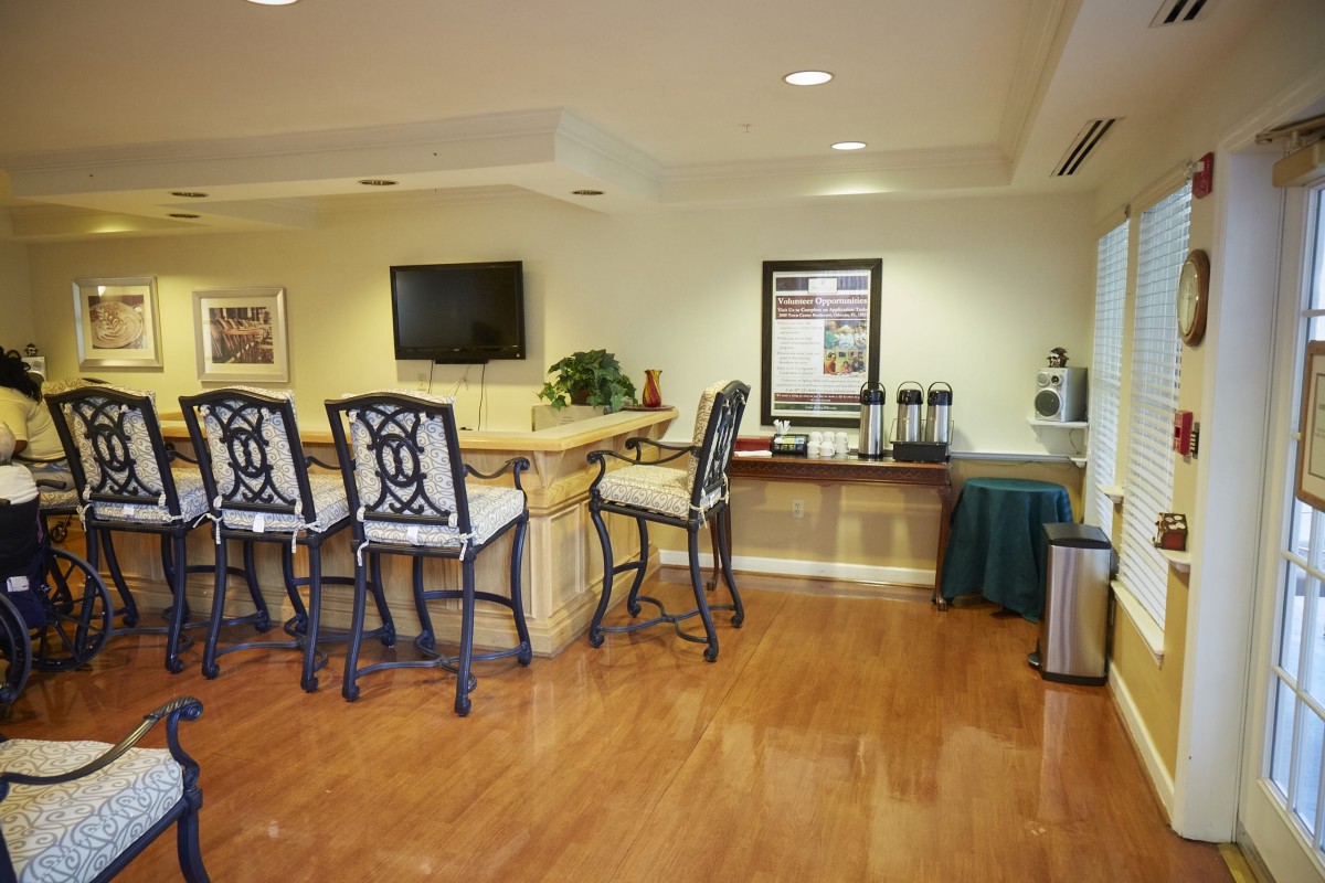 A cozy lobby area with a counter and seating, featuring a TV and a coffee station.