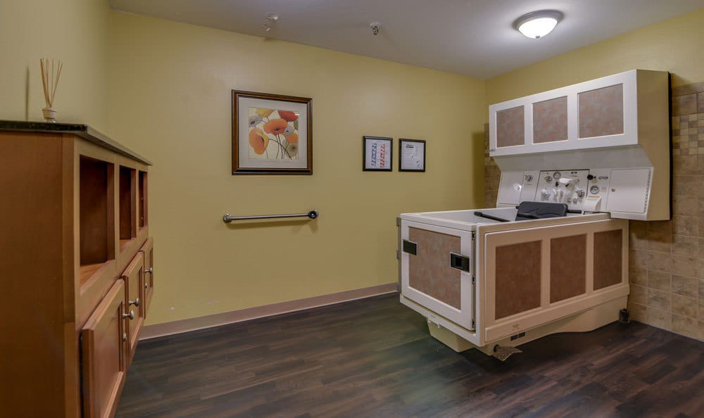 A kitchenette area in a medical facility with yellow walls and artwork on display.