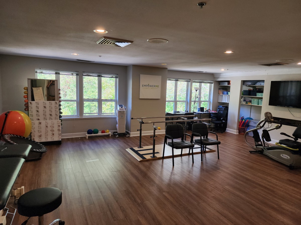A well-lit fitness room with exercise equipment and large windows.