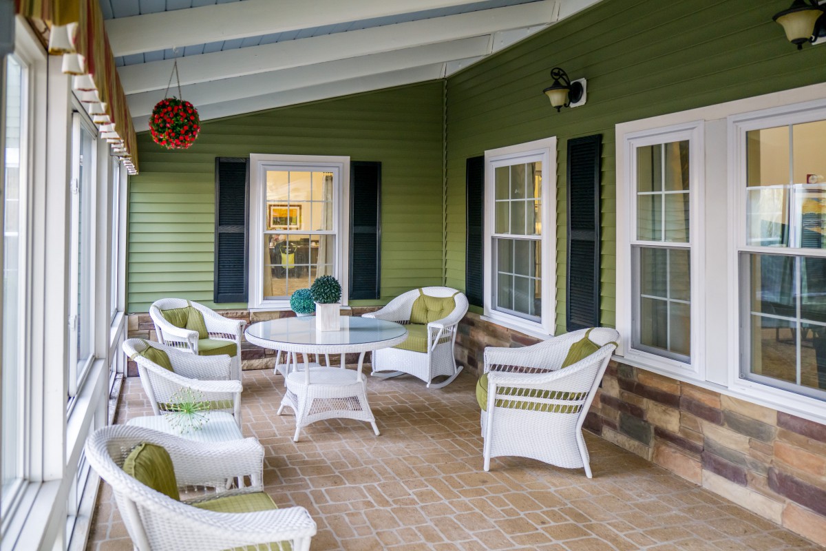 A cozy patio area with wicker furniture and green siding.
