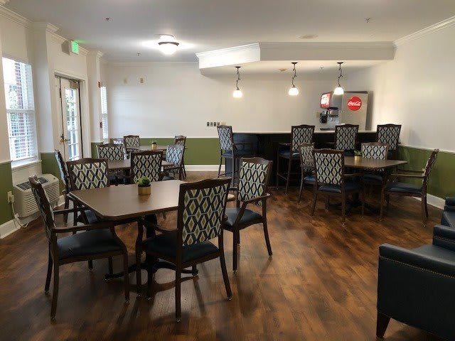 A cozy and modern dining area with tables, chairs, and a bar counter, featuring wooden flooring.