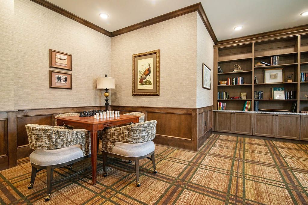 A cozy game room with a chess table and bookshelves.