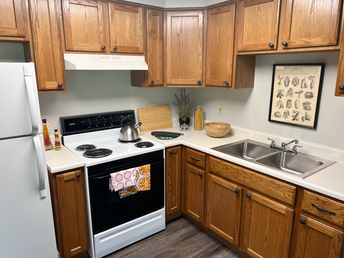 A cozy kitchen with wooden cabinets, featuring a stove, oven, and sink.