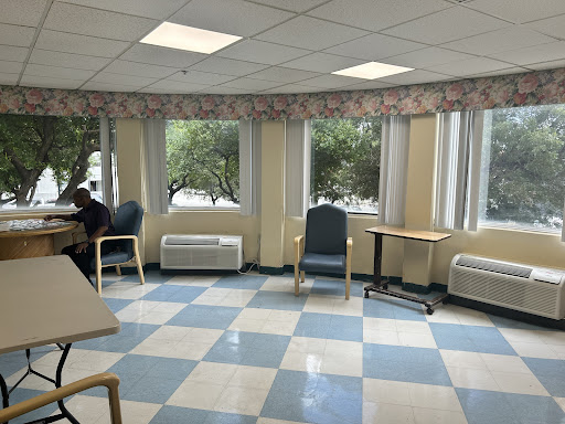 A bright waiting area with windows, featuring a blue and white checkered floor and comfortable seating.