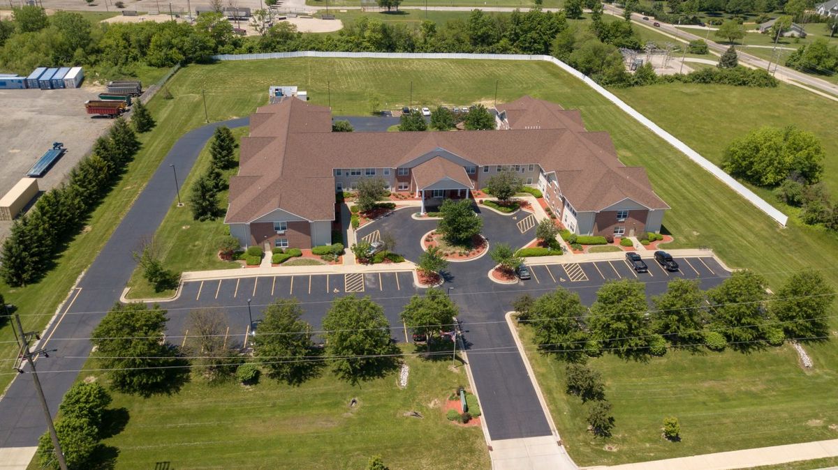 Aerial view of a large building complex surrounded by green lawn and parking area.