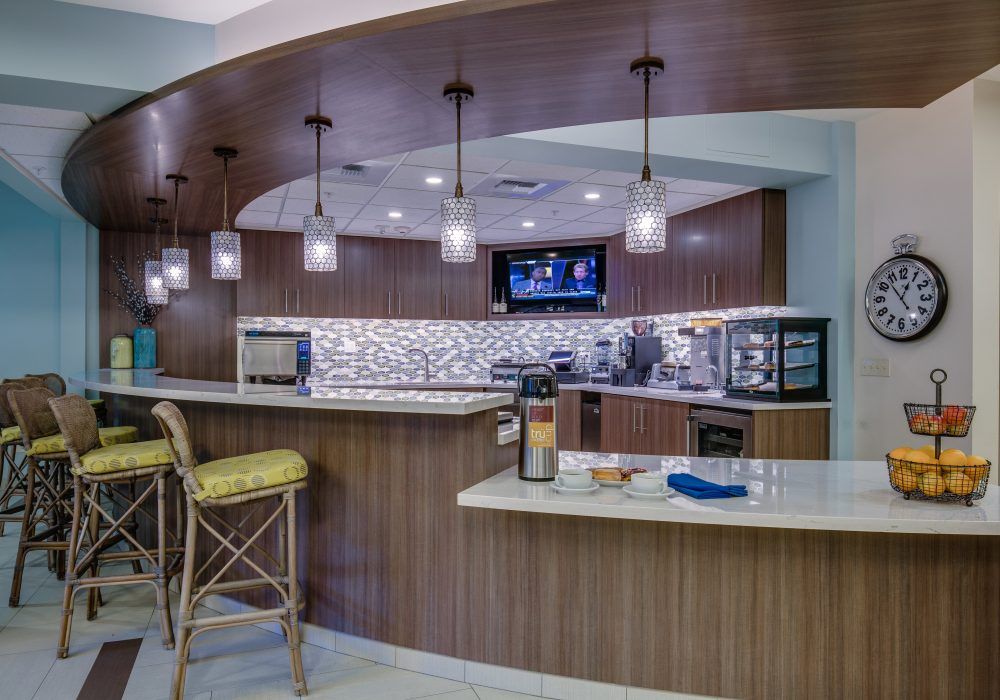 A modern bar interior featuring a stylish mosaic backsplash, pendant lighting, and comfortable seating.