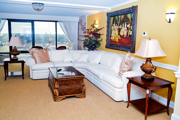A cozy living room with a large white sectional sofa, wooden coffee table, and decorative artwork on the wall.