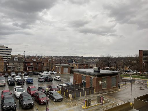 A view of a bustling parking lot amidst a cloudy day in an urban setting.