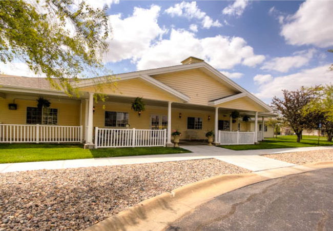 A charming residential house with a porch and well-maintained lawn under a clear sky.