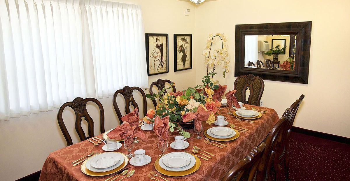 An elegantly set dining table with floral arrangements and decorative tableware.