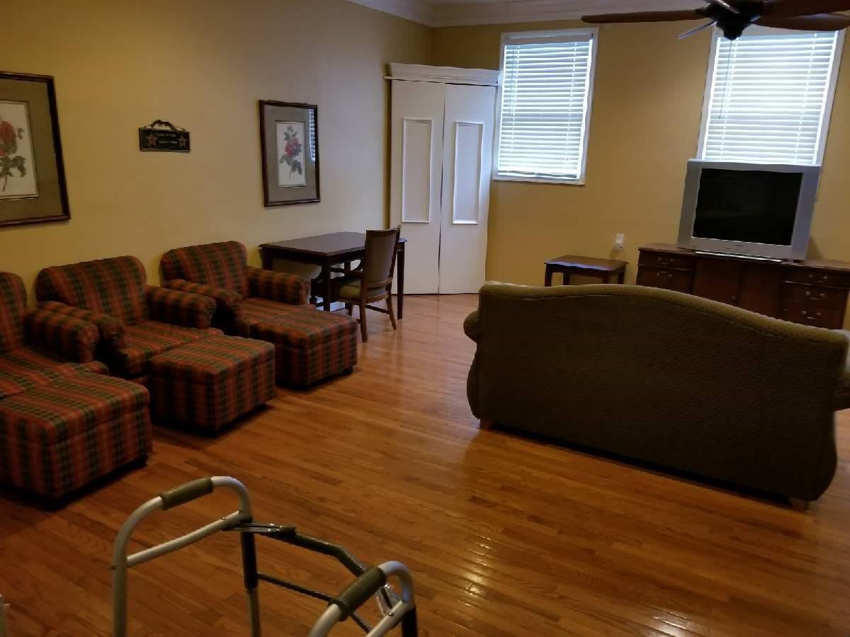 A cozy living room with chairs, a table, and a television on hardwood flooring.