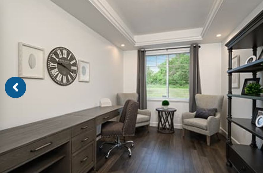 A modern home office with a desk, chairs, and a large window providing natural light.