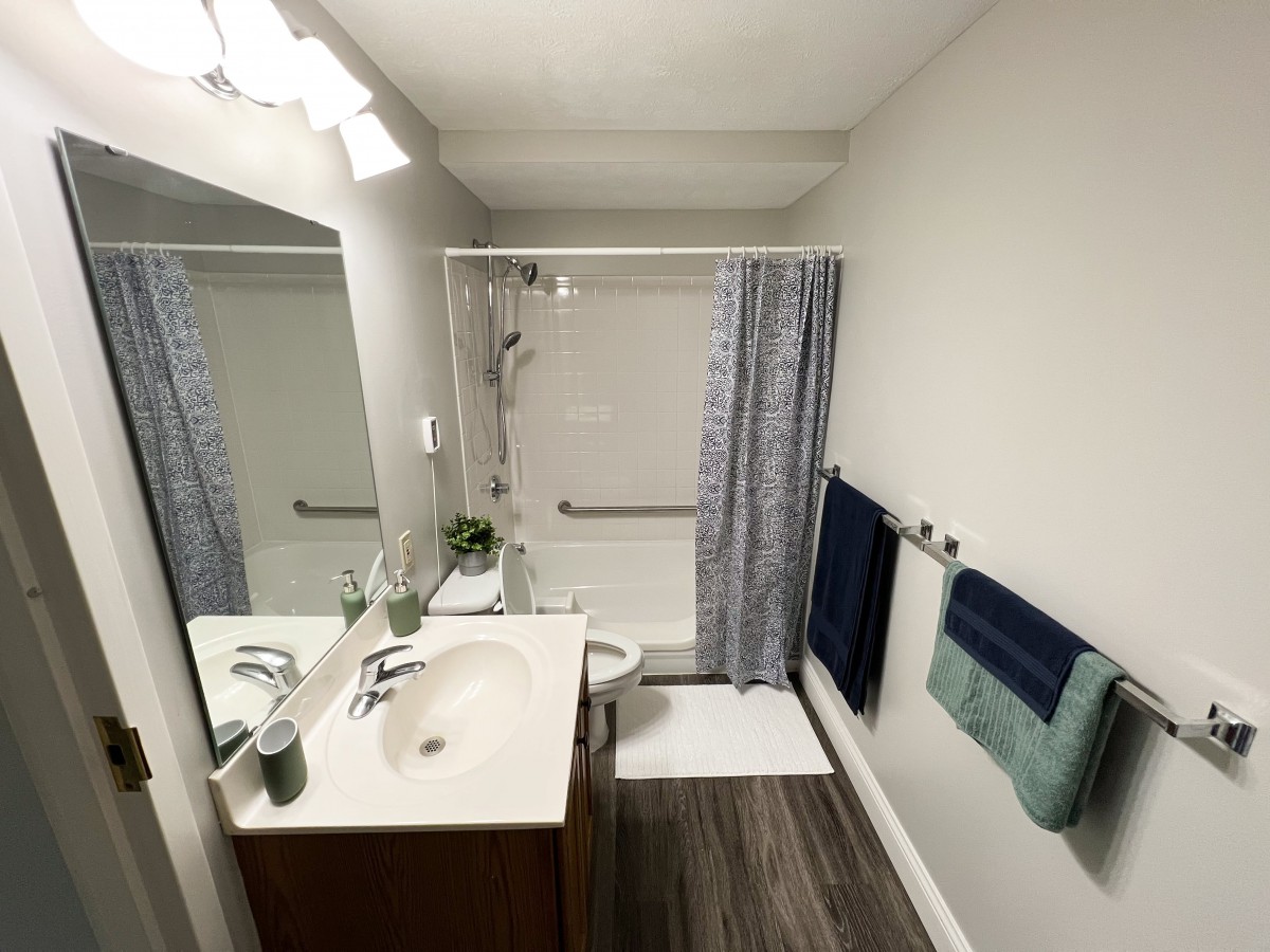 A modern bathroom with a sink, mirror, and shower.
