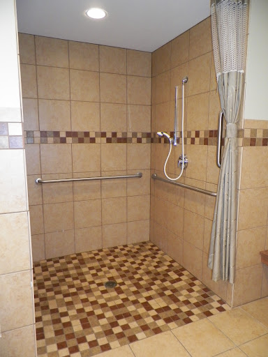 An accessible shower area featuring safety rails and a tiled floor.