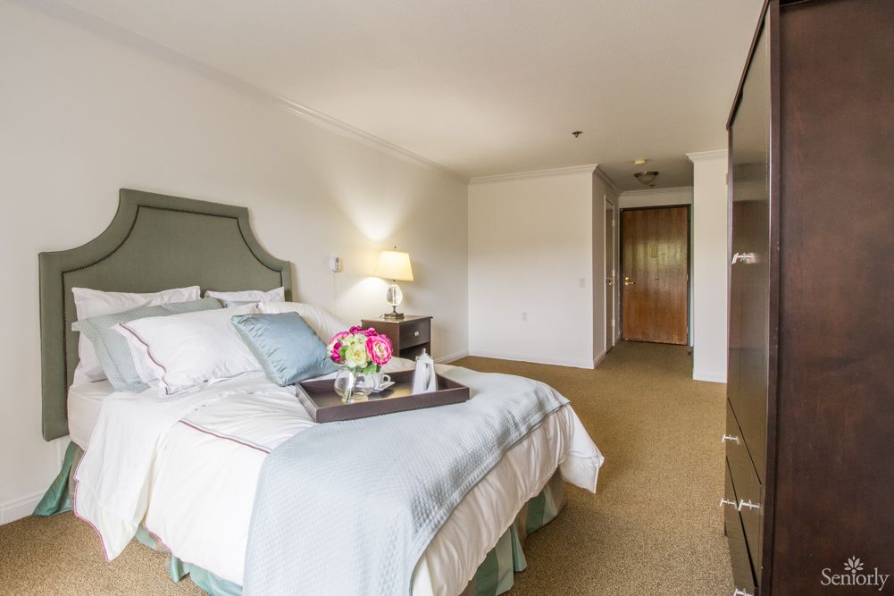 A well-decorated bedroom featuring a comfortable bed and bedside tray with flowers.