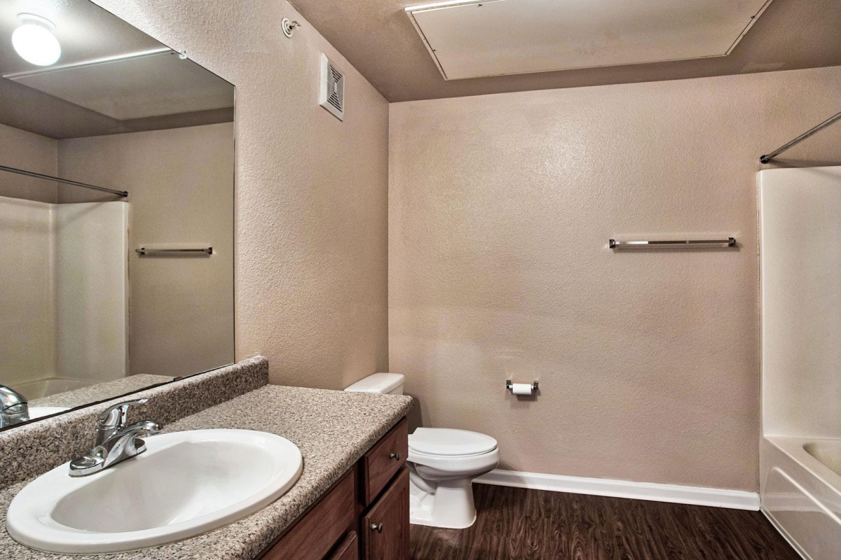A simple bathroom with a sink, toilet, and mirror.