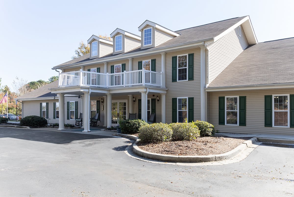 A two-story residential building with a porch and well-maintained landscaping.
