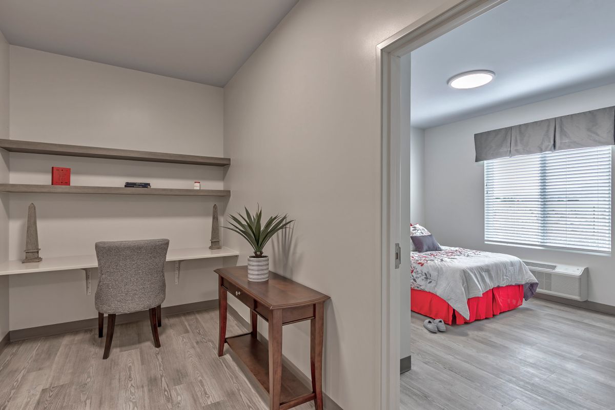 A modern minimalist home office adjacent to a cozy bedroom.