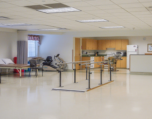 A spacious rehabilitation room equipped with therapy bars and exercise equipment.
